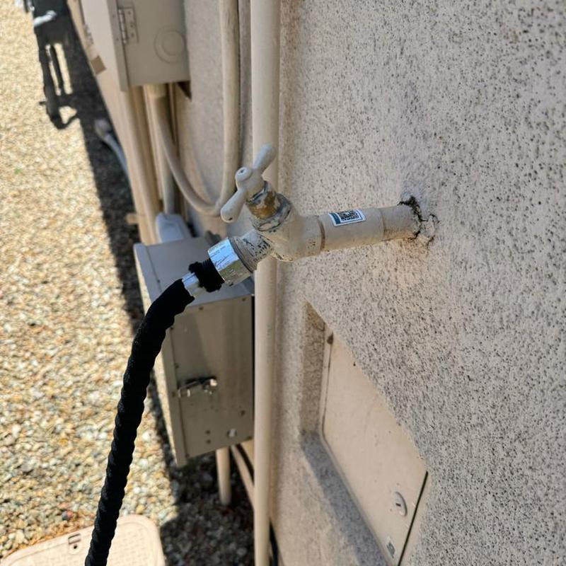Hose bib with seized garden hose attached on exterior wall