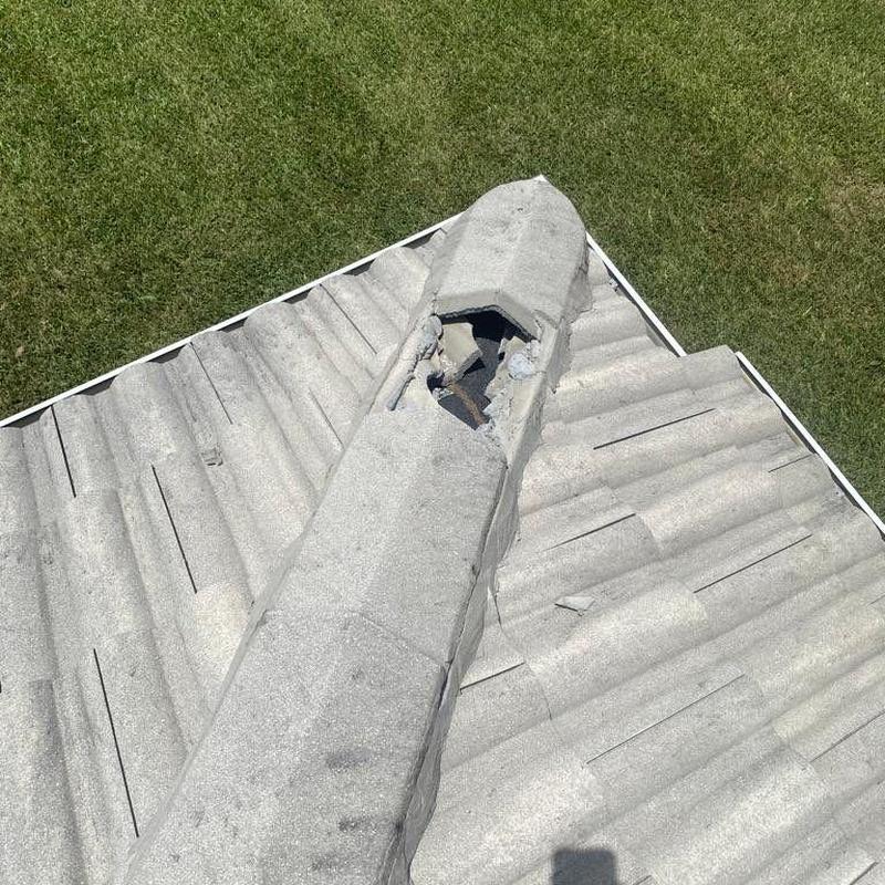 Concrete tile roof ridge with damaged tiles and debris