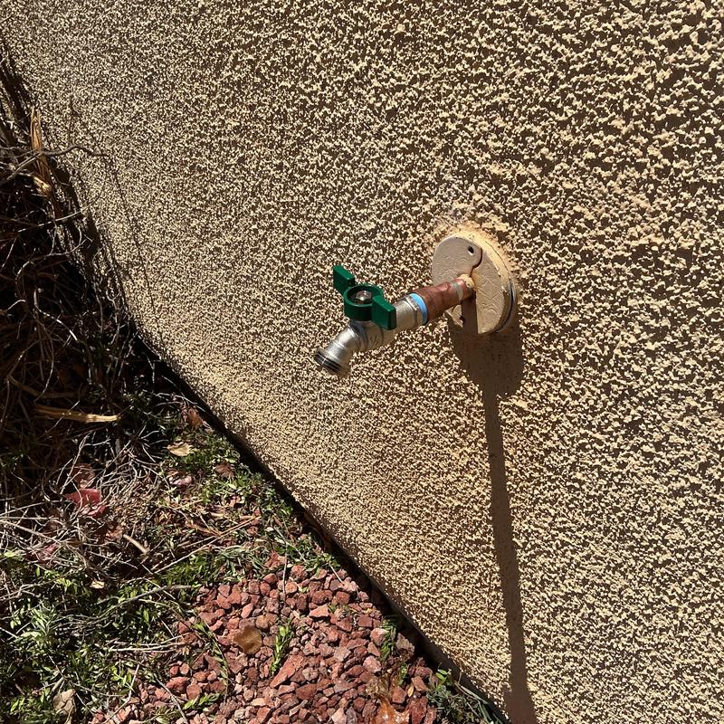 Outdoor hose bib with green handle on stucco wall Outdoor hose bib with green handle on stucco wall