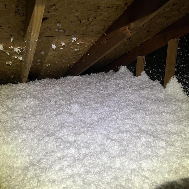 Attic loose-fill insulation installed under roof beams