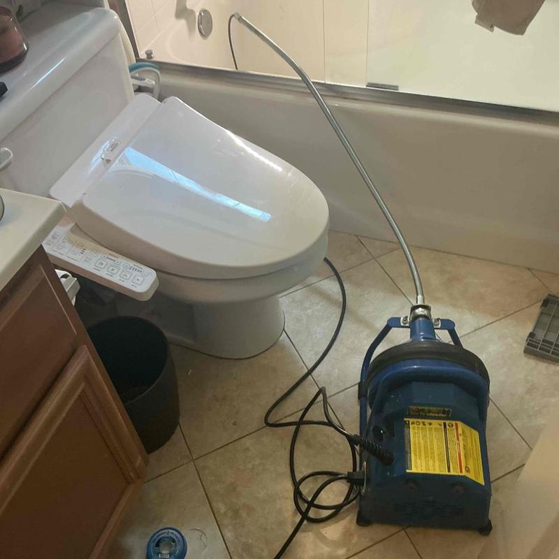 Bathtub drain clogging machine with cable in bathroom