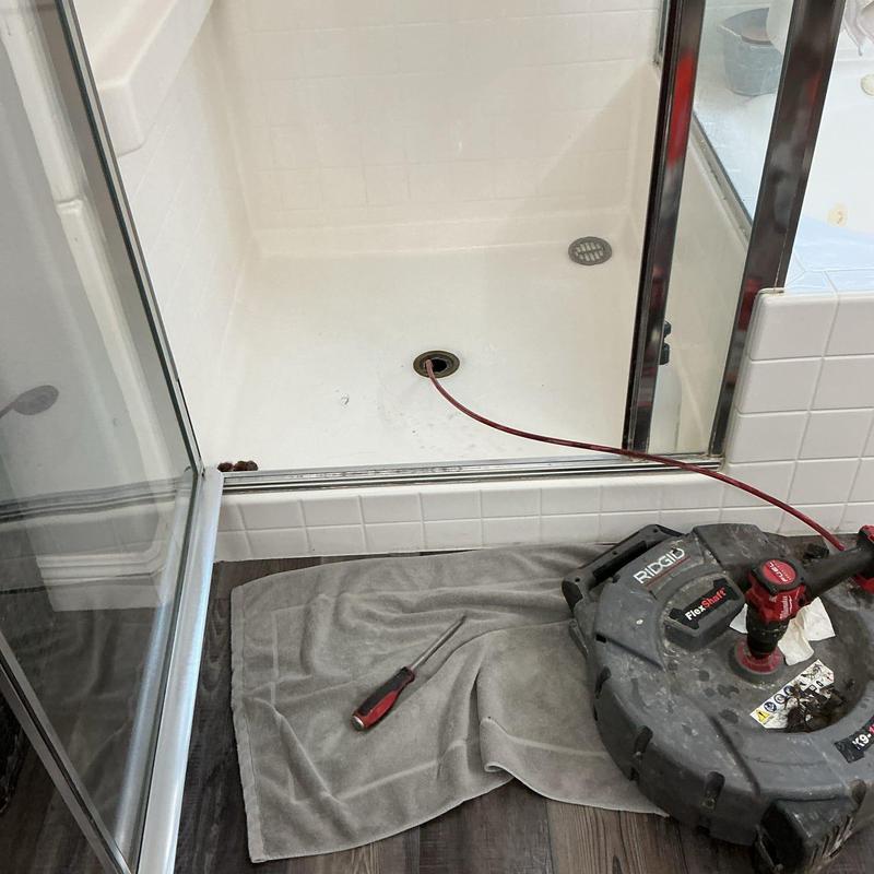 Shower drain with plumbing snake and screwdriver