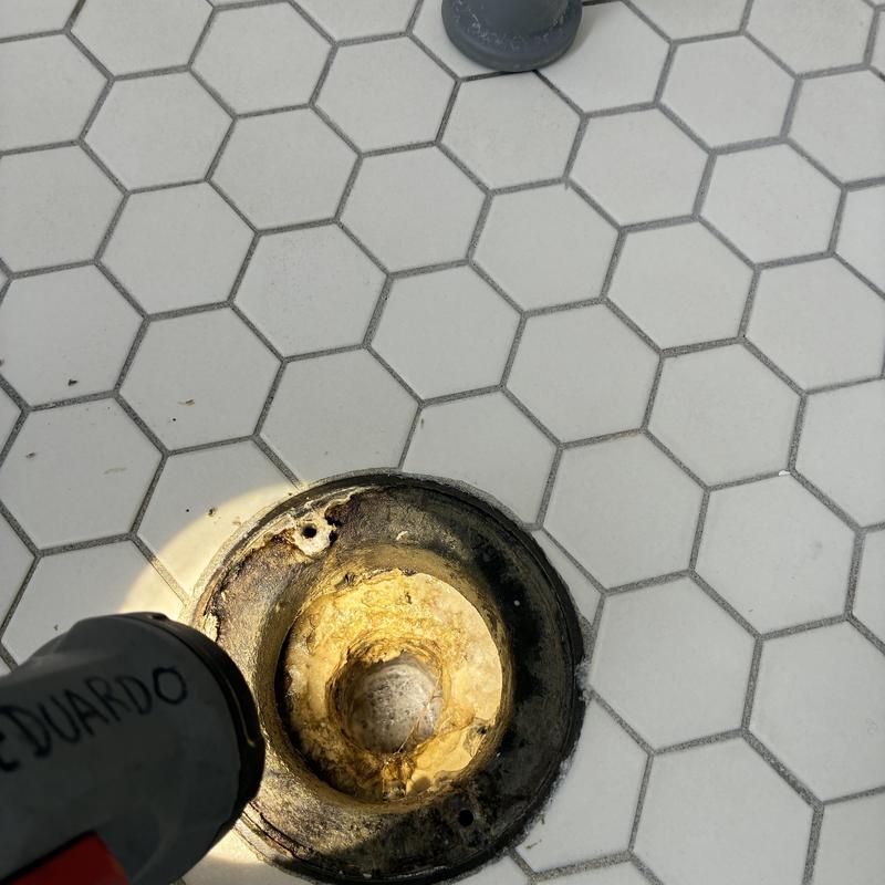 Shower drain with hair clog buildup in hex tile floor Shower drain with hair clog buildup in hex tile floor