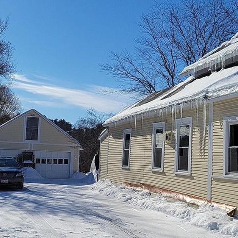 Asphalt shingle roof with icicles in winter
