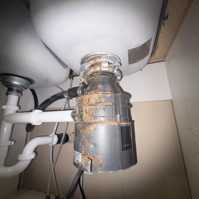Garbage disposal drain with corrosion and leaks under sink