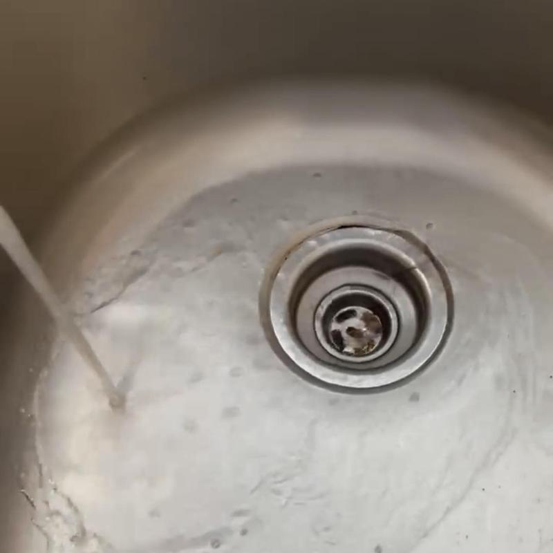 Kitchen sink drain with flowing water clearing blockage