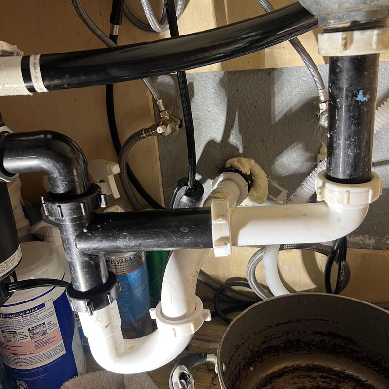 Kitchen sink drain pipes under cabinet with clog tools