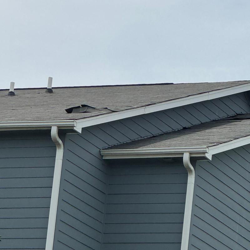 Asphalt shingle roof with visible damage on residential building
