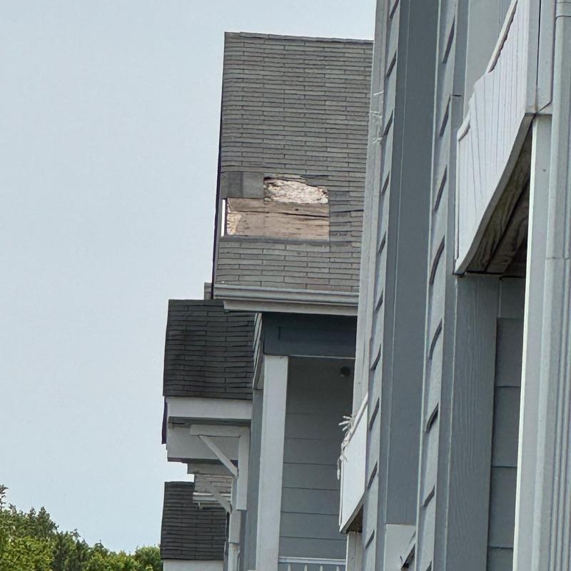 Apartment shingle roof with damaged section visible