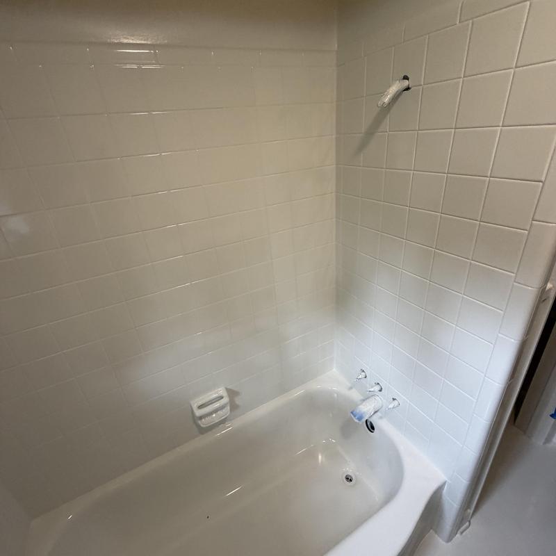 Bathtub and tile refinishing in white bathroom corner