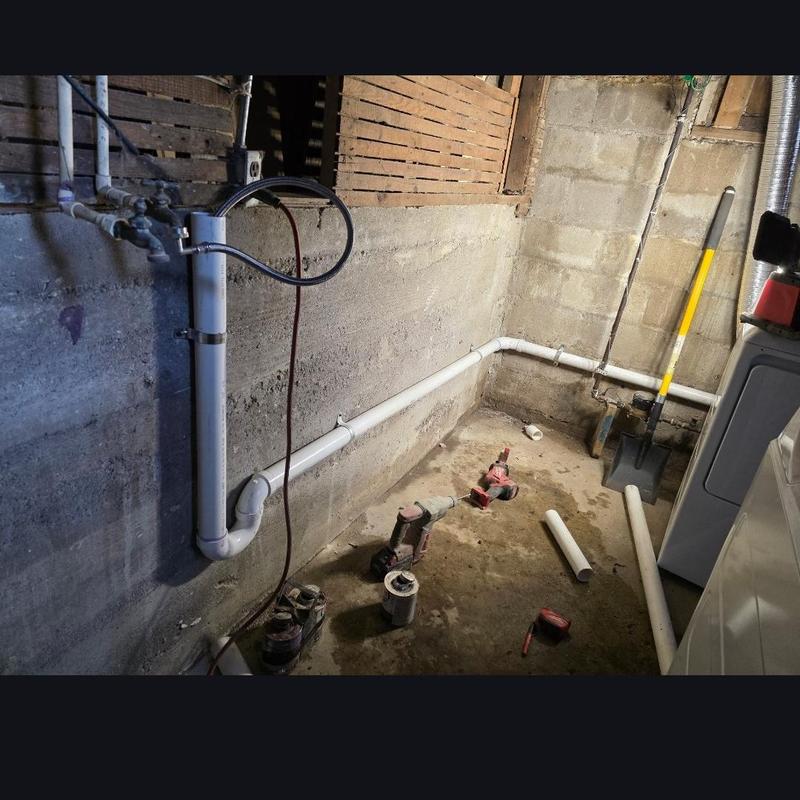 Laundry drain pipe installation and plumbing tools in basement