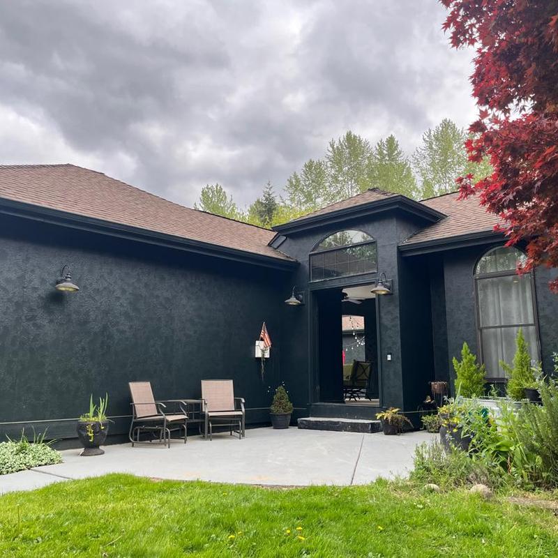 Asphalt shingle roof on dark stucco house exterior