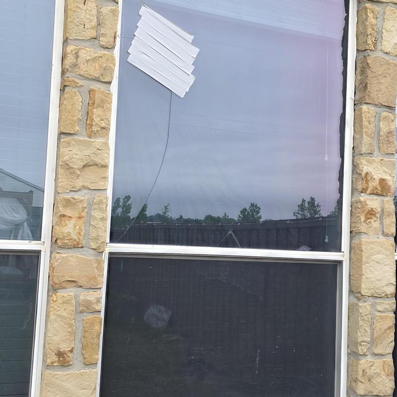 Window glass with cracks from hail damage in stone wall