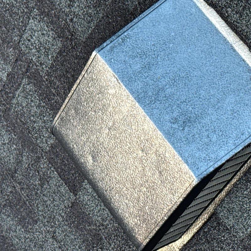 Metal roof ventilation cover showing hail damage on shingles