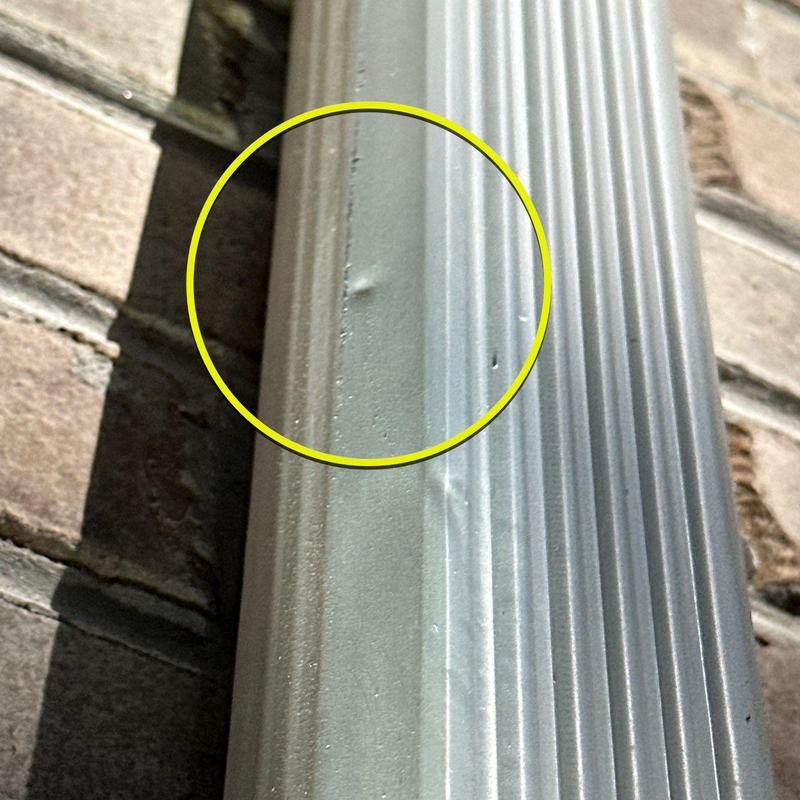 Metal flashing with hail damage dents on roof edge