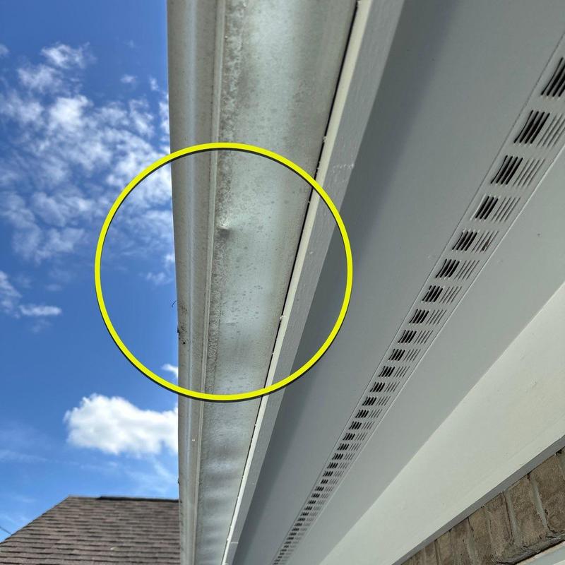 Metal gutter with dent damage under roof edge