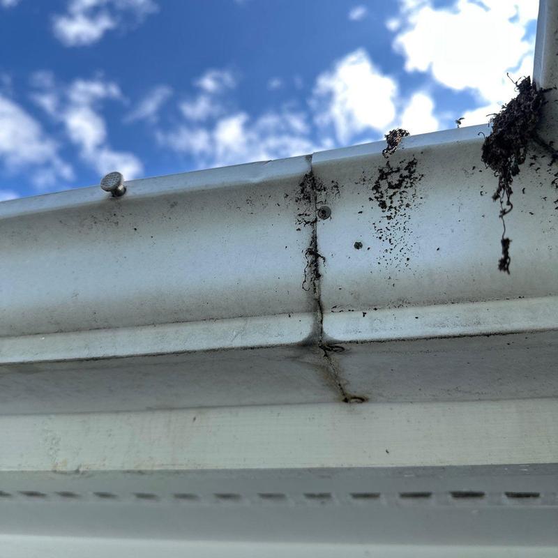 Gutter joint with rust and dirt buildup under blue sky