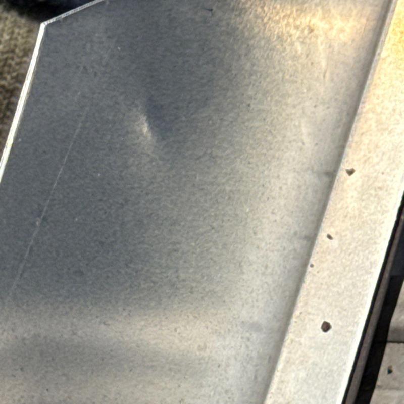 Metal roof panel dent from hail impact