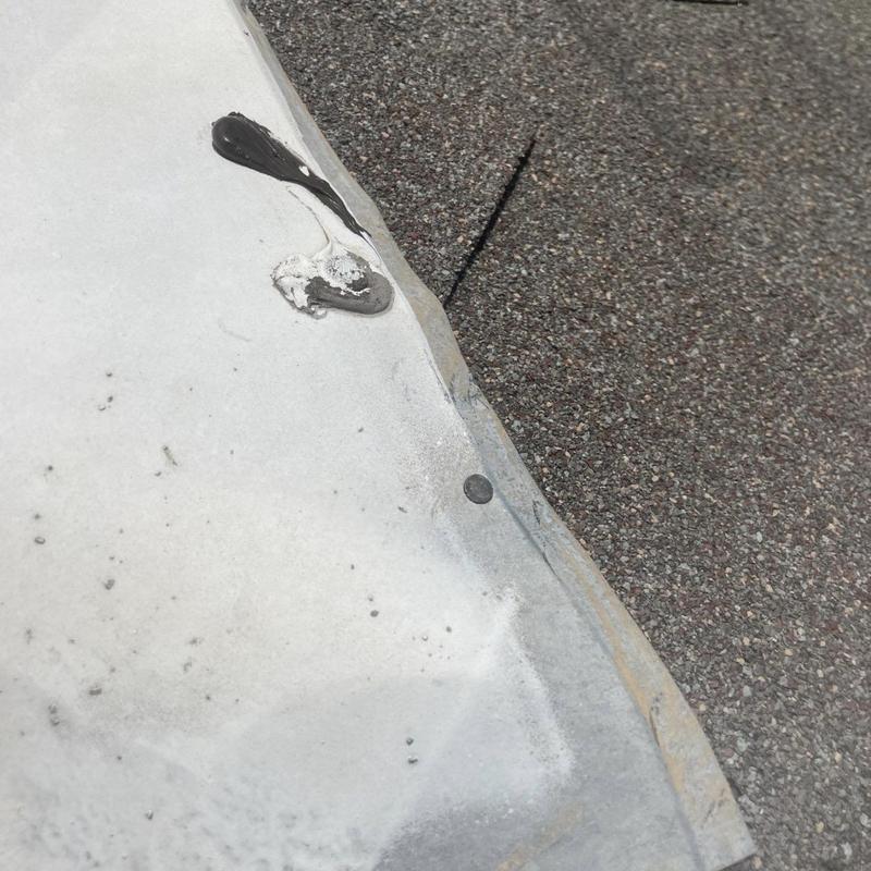 Roof-to-wall flashing with sealant on shingle roof edge
