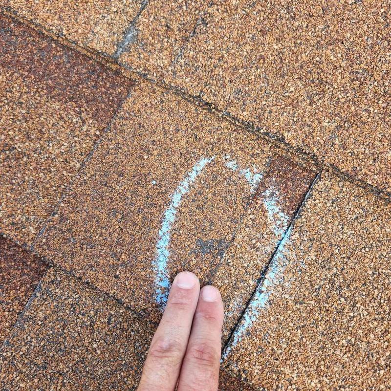 Asphalt roof shingle with damage marked for inspection