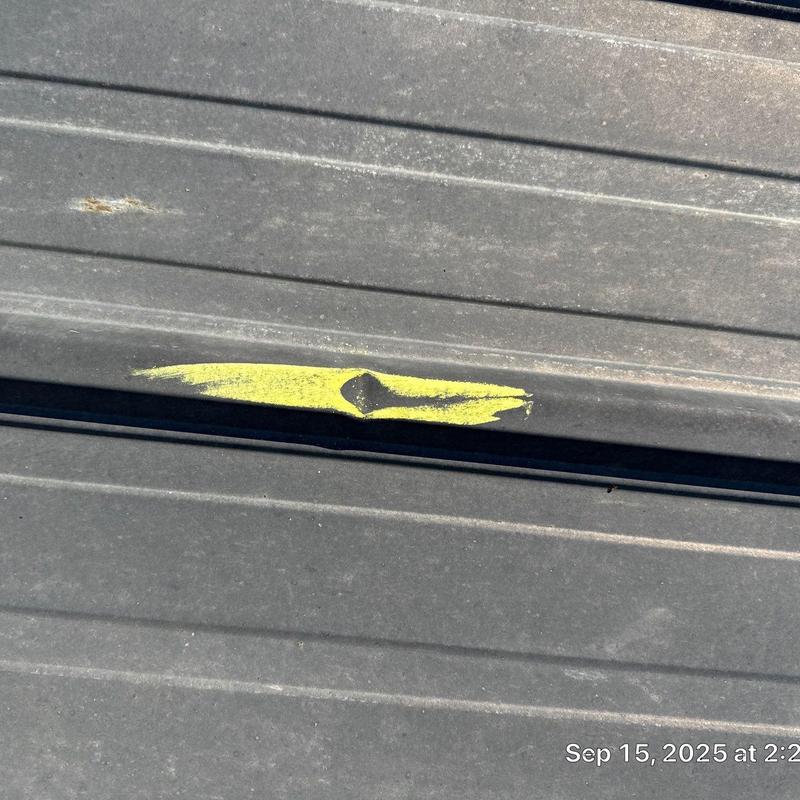 Metal roof panel hail damage marked with yellow paint