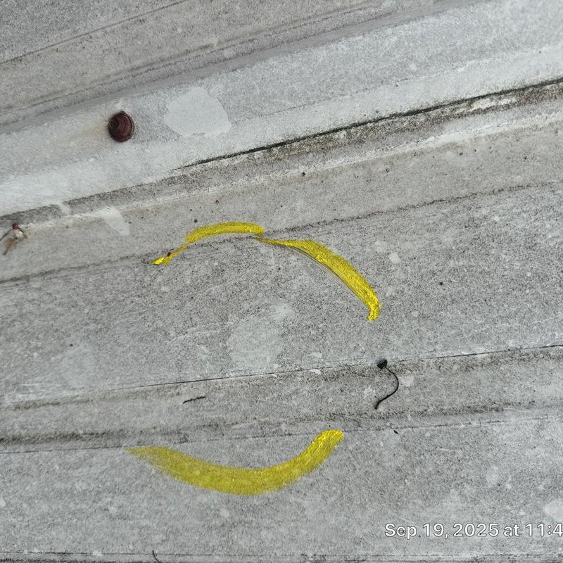 Roof metal panel with hail damage marked in yellow paint