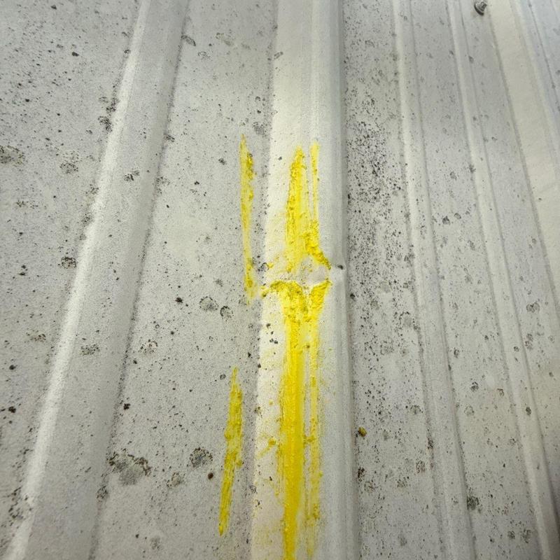 Metal roof panel hail damage with yellow marker highlights