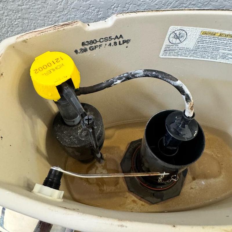 Toilet fill valve with yellow cap in tank
