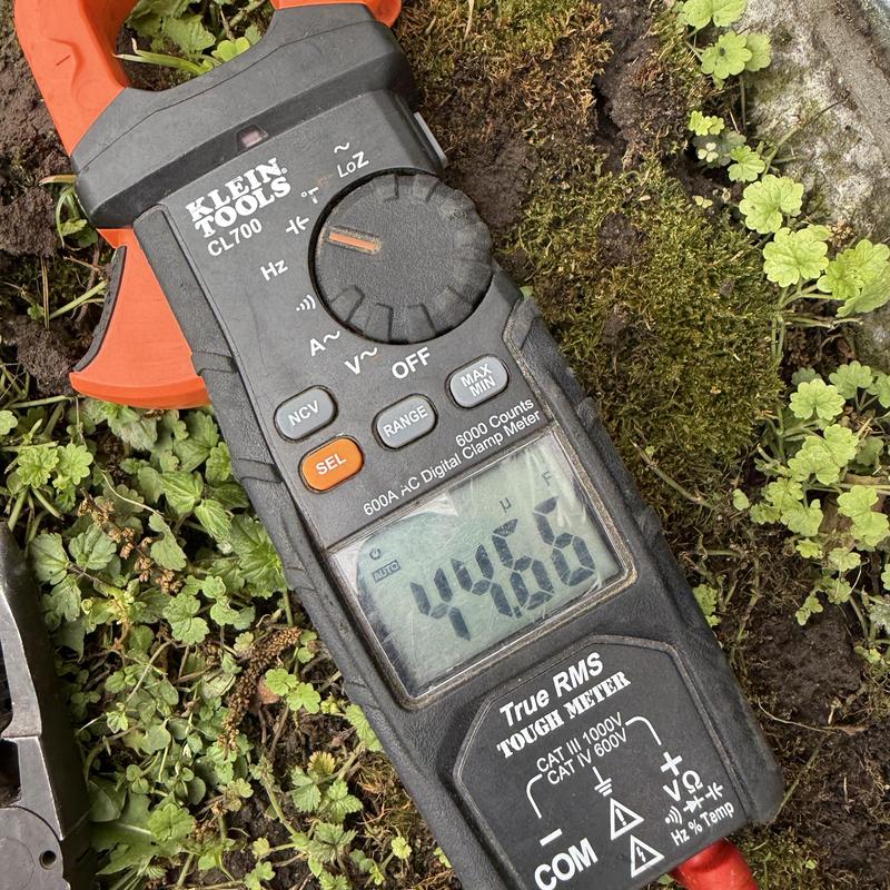 Digital clamp meter displaying 44.66 reading on grass Digital clamp meter displaying 44.66 reading on grass