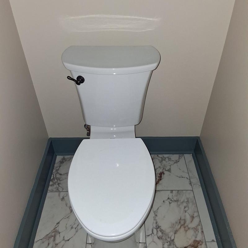 Toilet with flush handle in small bathroom corner