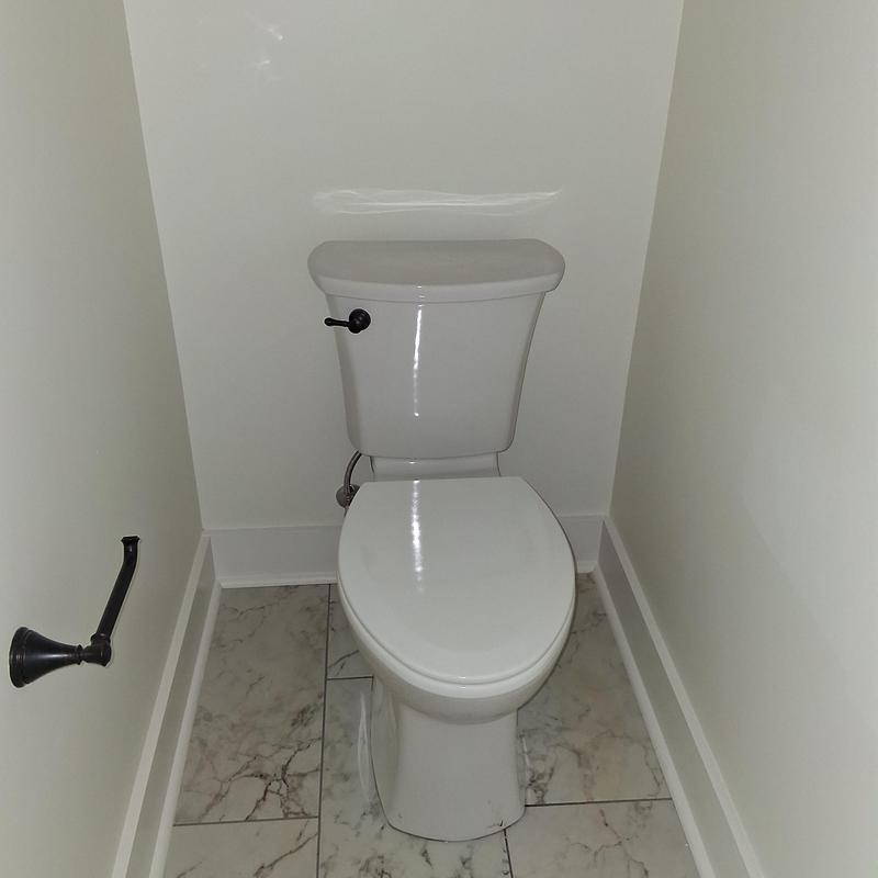 Toilet unit with closed lid and marble tile floor