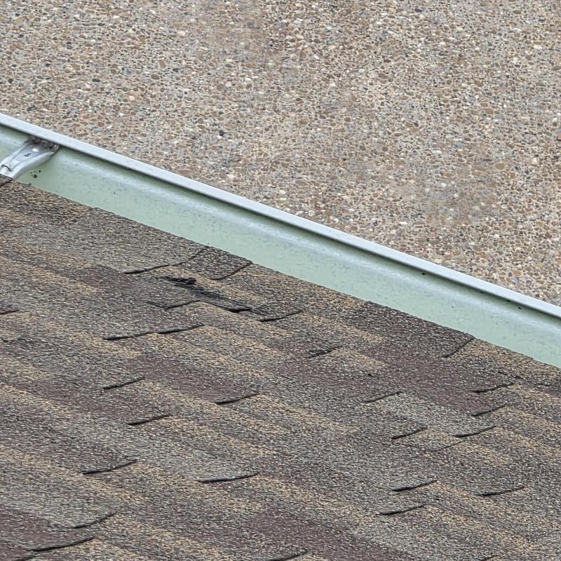 Asphalt shingles with hail damage near gutter edge