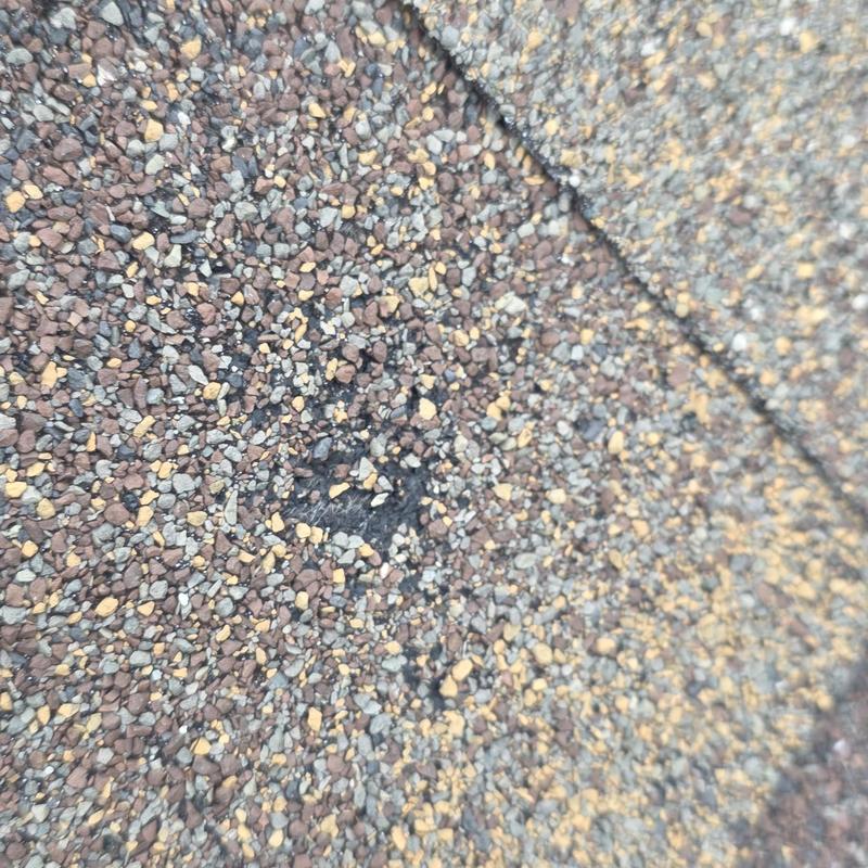 Asphalt shingle close-up showing hail damage spot