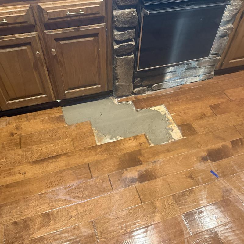 Slab leak repair site on hardwood kitchen floor