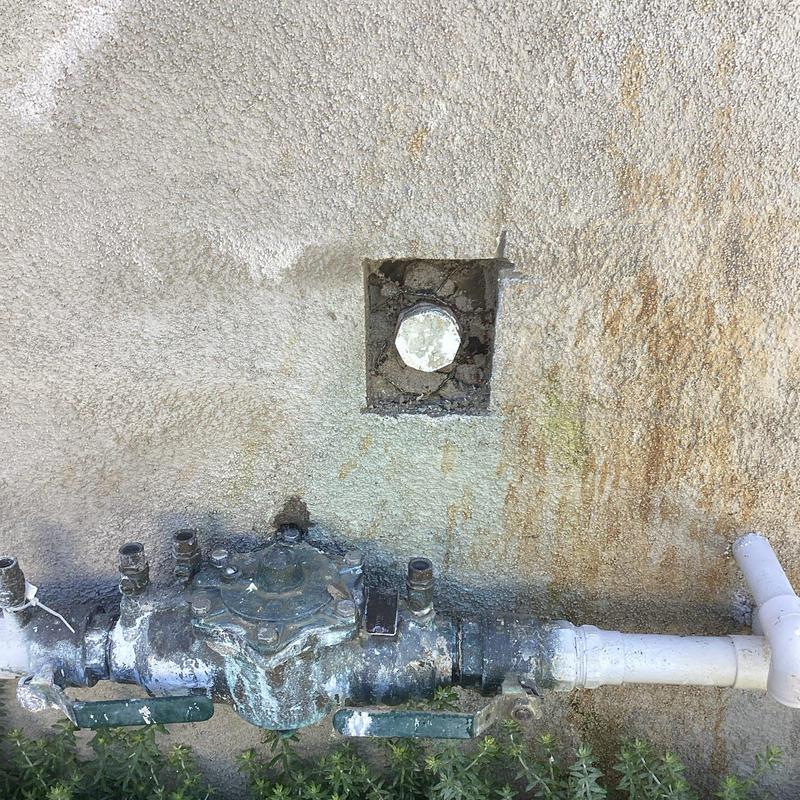 Main water line with loose test cap in stucco wall