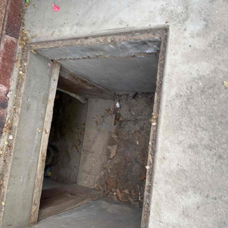 Basement stairwell with dirt floor and debris inside