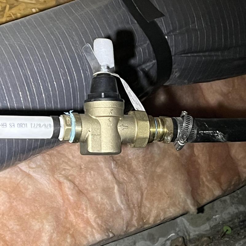 Pressure reducing valve with attached pipes in crawlspace