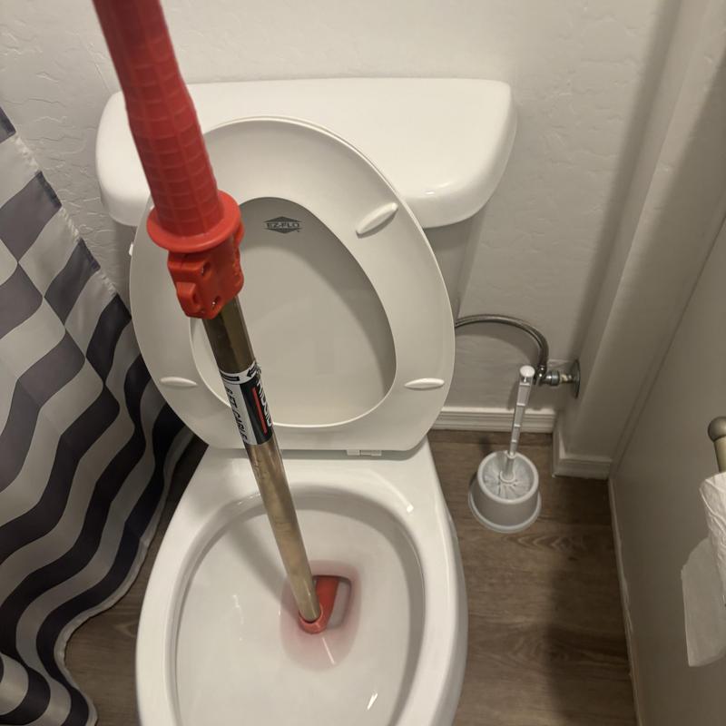 Toilet bowl with auger tool clearing clog Toilet bowl with auger tool clearing clog