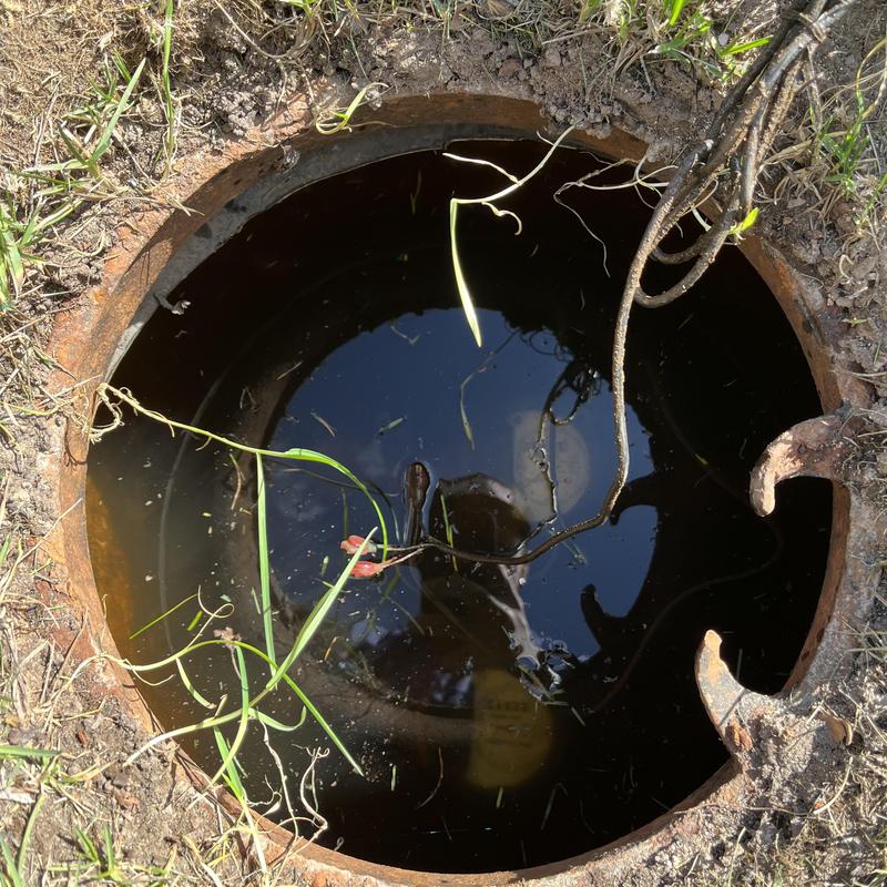 Water meter pit flooded with standing water outdoors