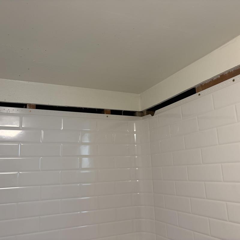 Bathroom shower tile with removed trim for pipe access