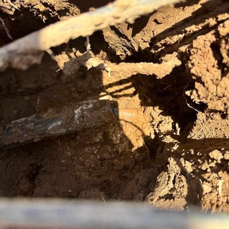 1 1/4-inch PEX water main exposed in dirt trench