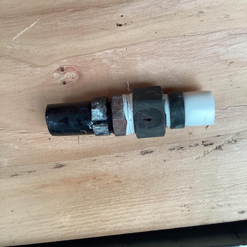 Plastic water line connector with fittings on wood surface