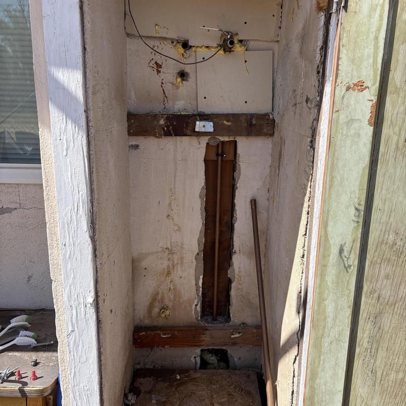 Water heater plumbing removal area with exposed pipes