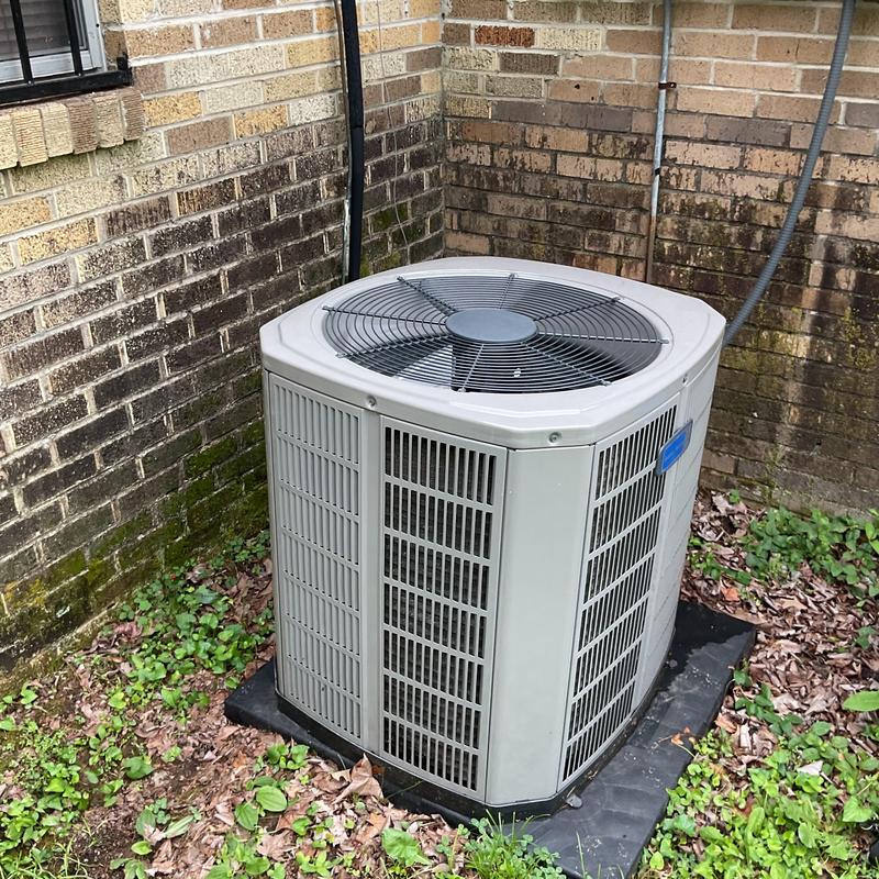 Air conditioner condenser unit beside brick wall outdoors