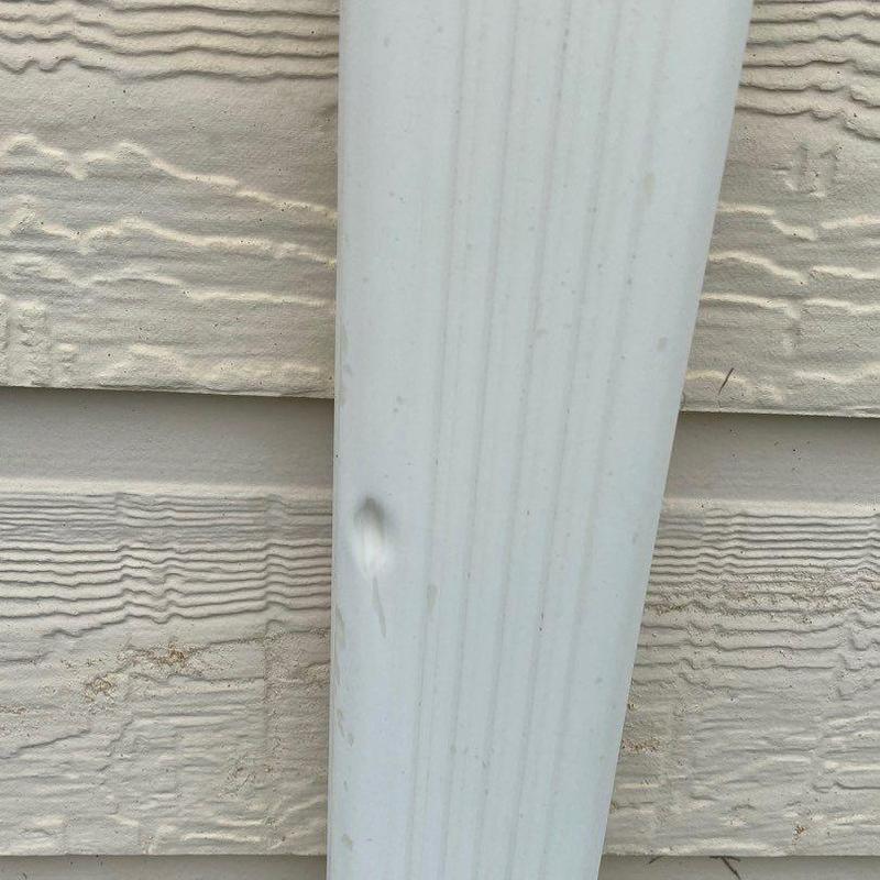 Downspout with visible dent on beige siding background