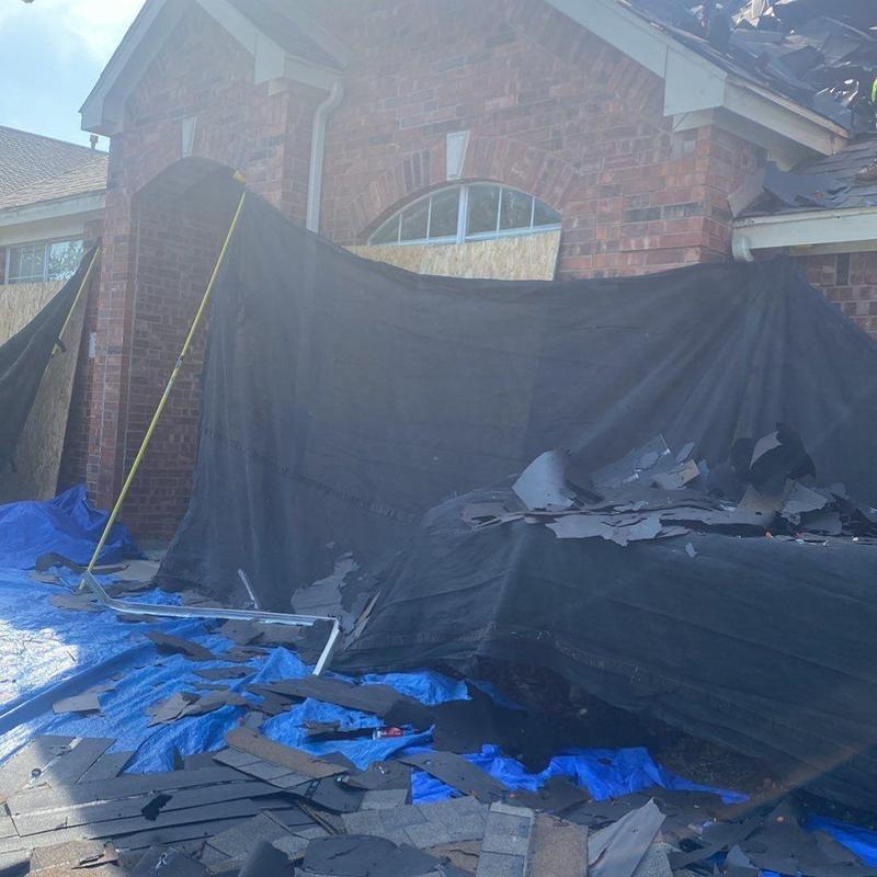 Roof shingles debris with protective tarp outside brick house