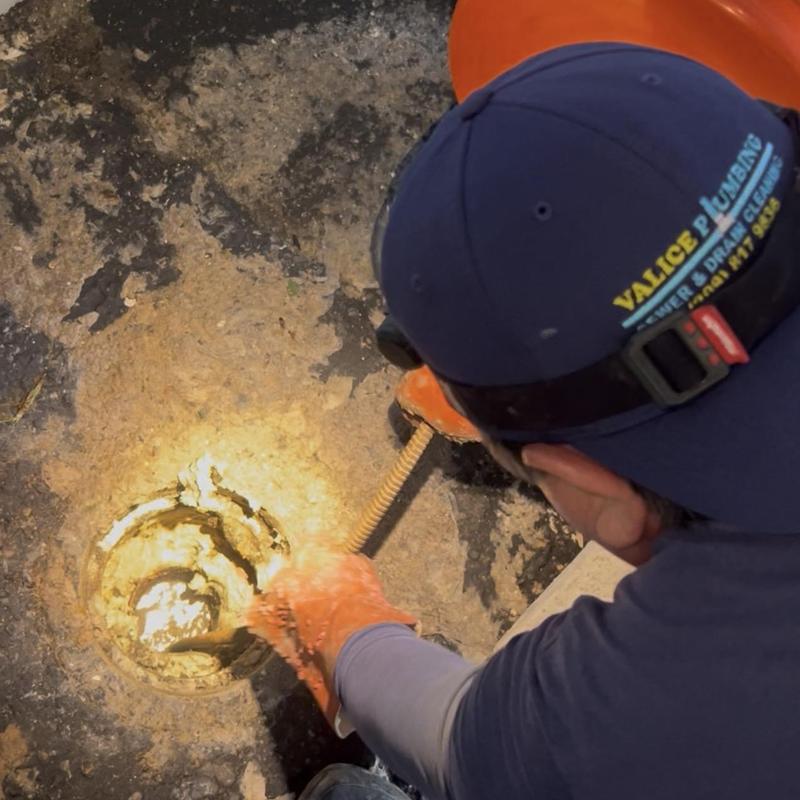 Main drain sewer cleaning with plumbing snake in floor