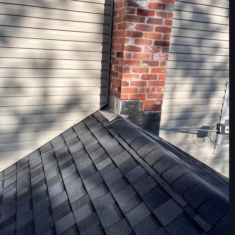 Roof chimney flashing with black asphalt shingles