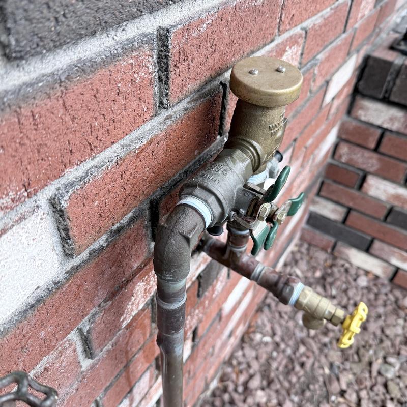 Backflow preventer on irrigation system near brick wall Backflow preventer on irrigation system near brick wall