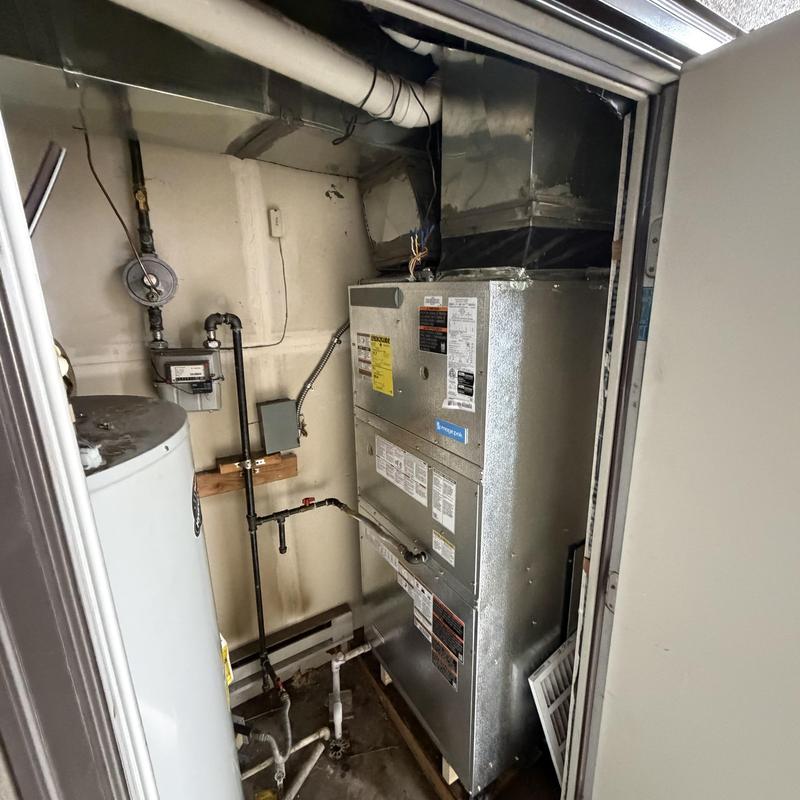 HVAC air handler and water heater setup in utility closet